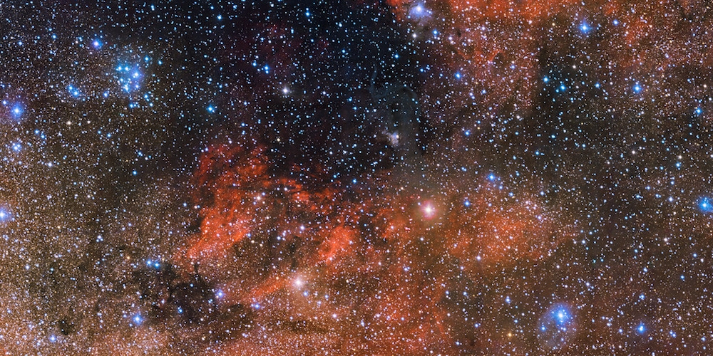De kleine opeenhoping van heldere blauwe sterren in de linker bovenhoek van deze enorme nieuwe 615 megapixel ESO-opname is een perfect kosmisch laboratorium voor het onderzoek van de levensloop van sterren